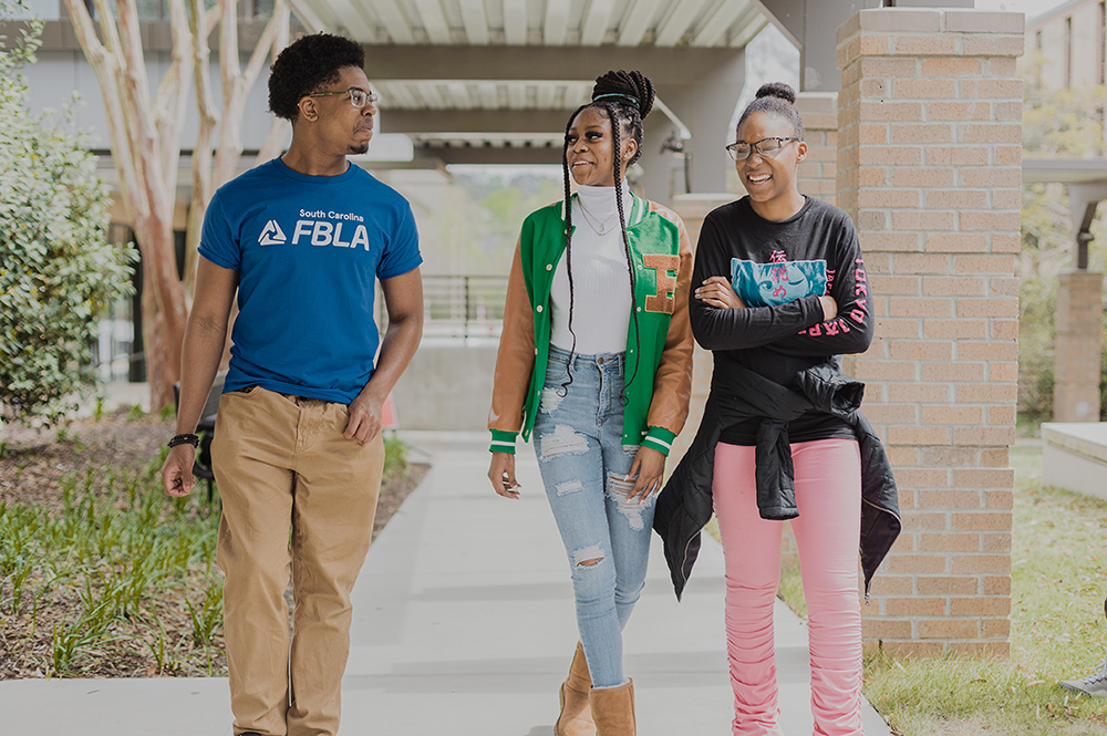 one black male and two black female students walking on campus